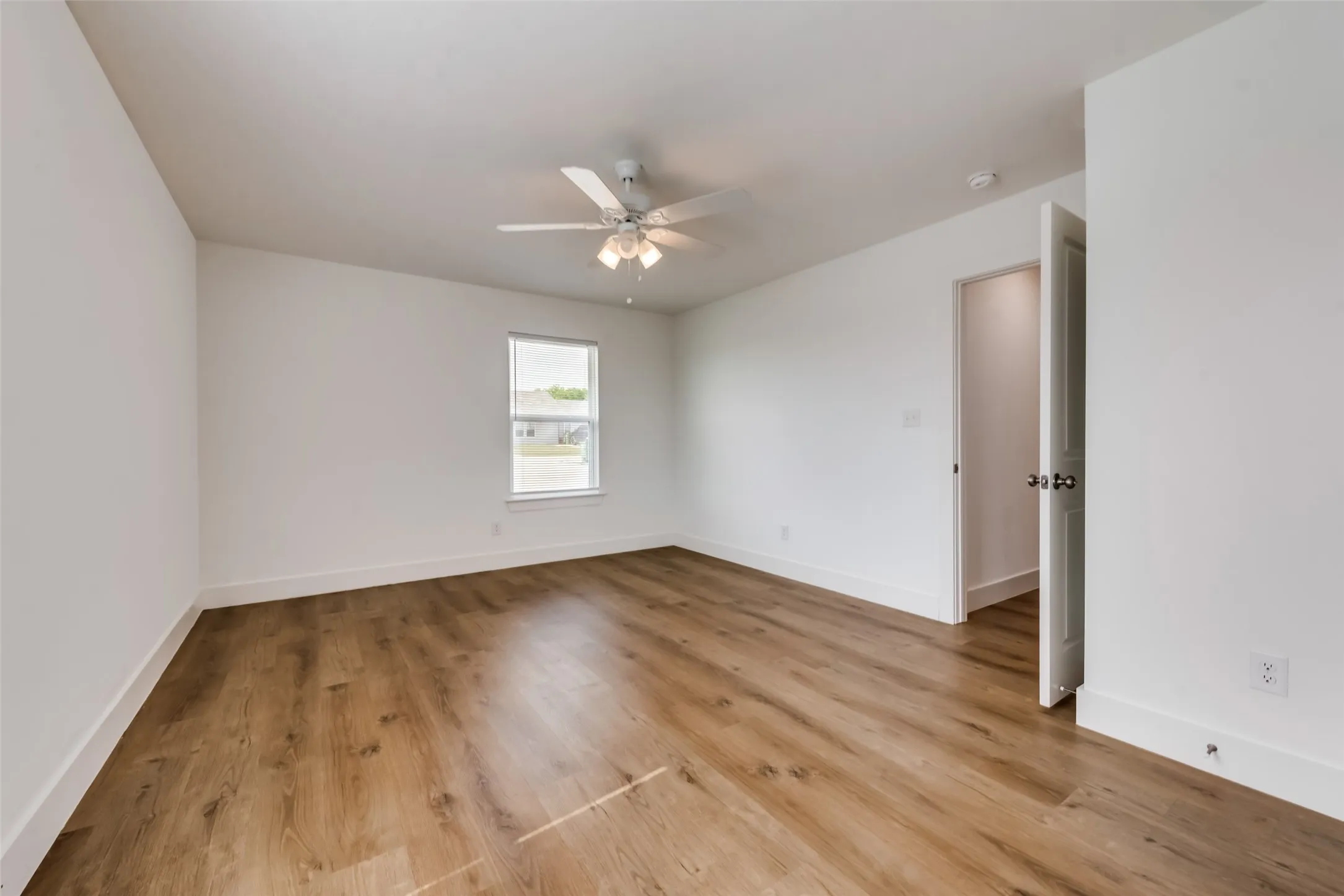 Wood-finish flooring, white walls, and a ceiling fan with integrated lighting