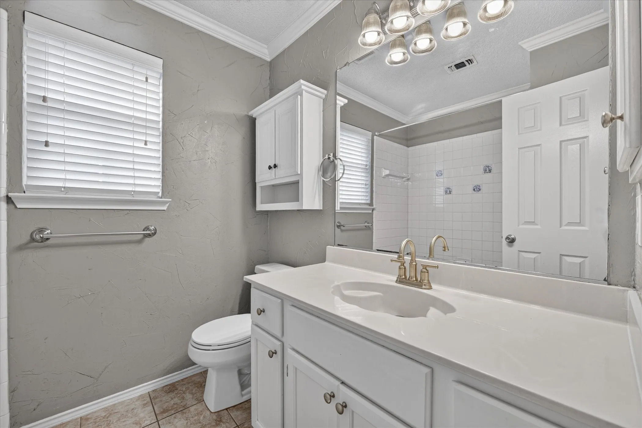 White vanity with an integrated sink, brushed nickel faucet, wall-mounted mirror, and white wall cabinet