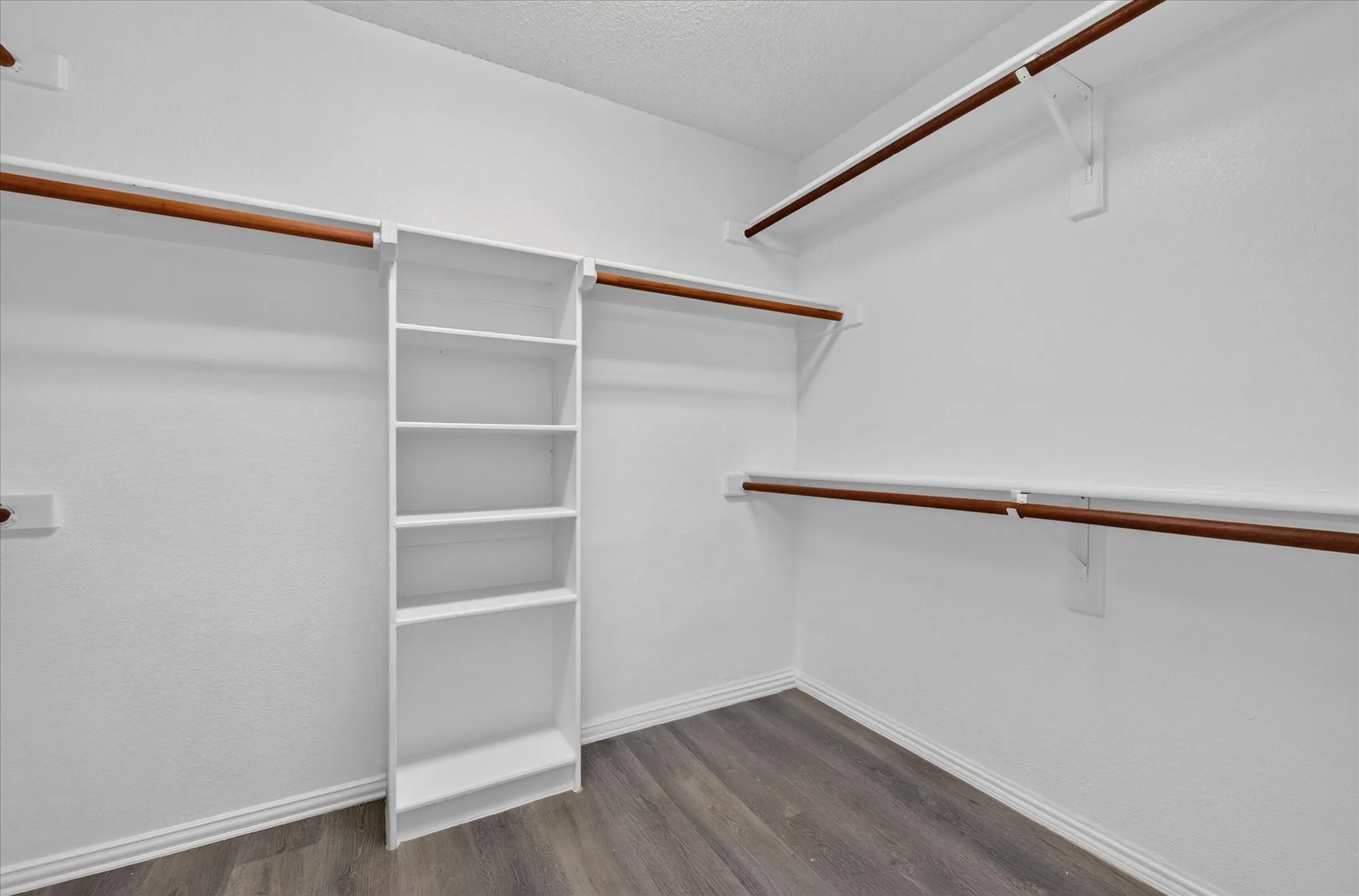 Built-in shelving unit, multiple clothing rods, and wood-finish flooring