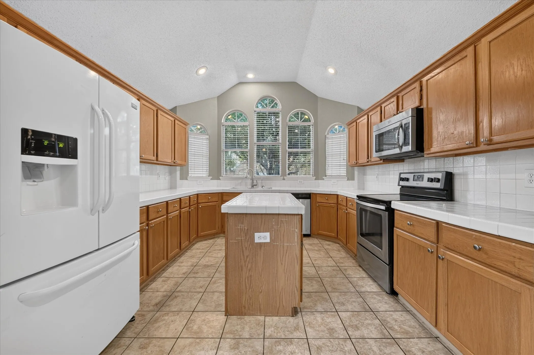 U-shaped kitchen with wood-finish cabinetry, tile flooring, white tile countertops, and a white tile backsplash