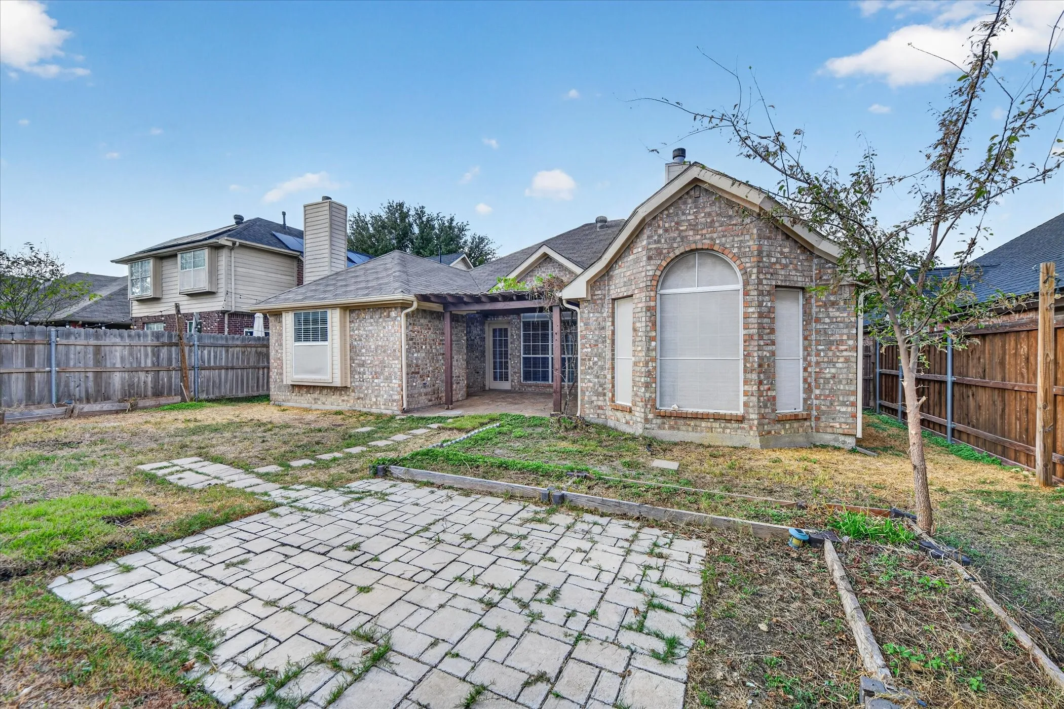 Brick exterior with arched window, patio access, and a paved hardscape area