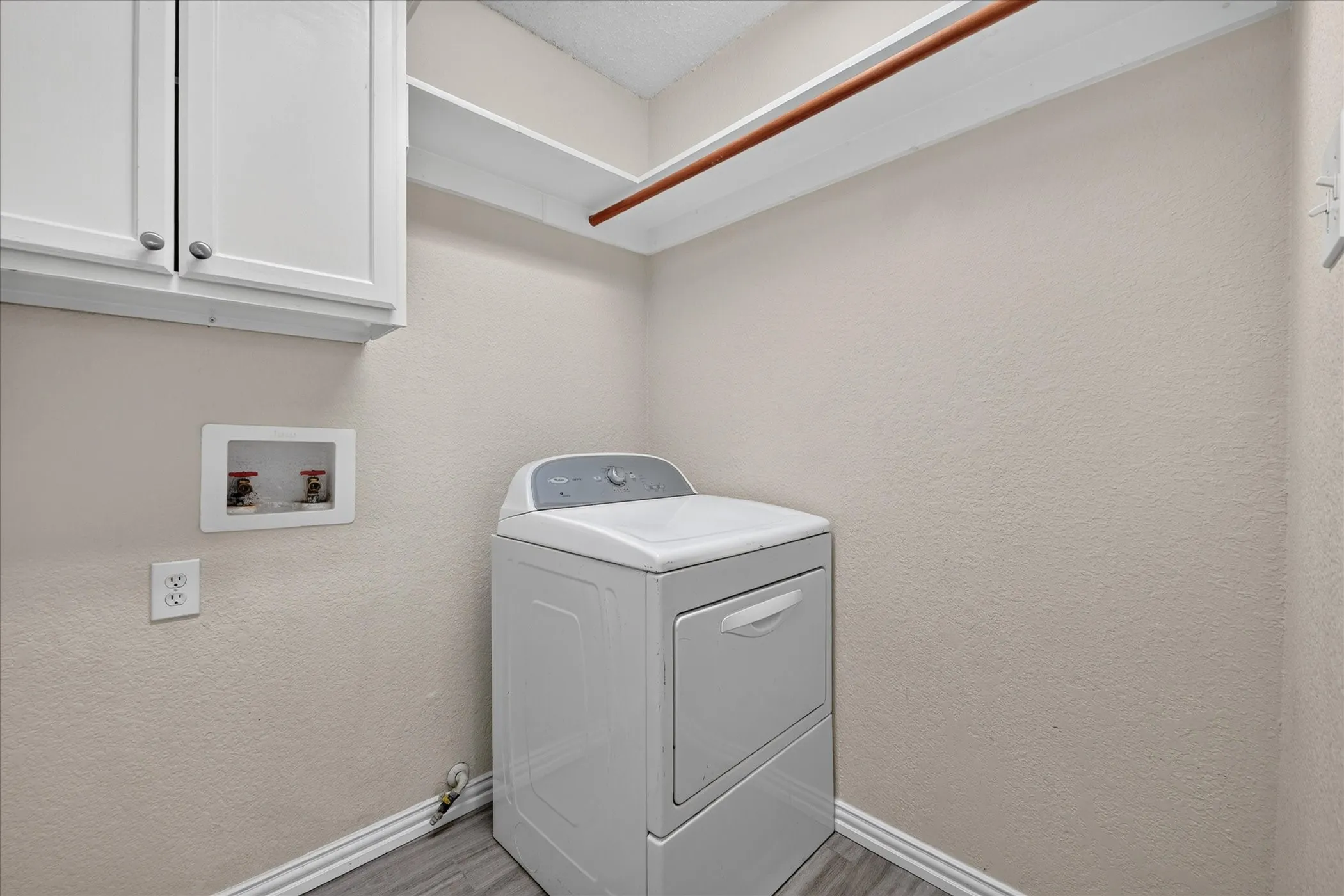 Utility room featuring white cabinetry, built-in shelving, and wood-finish flooring