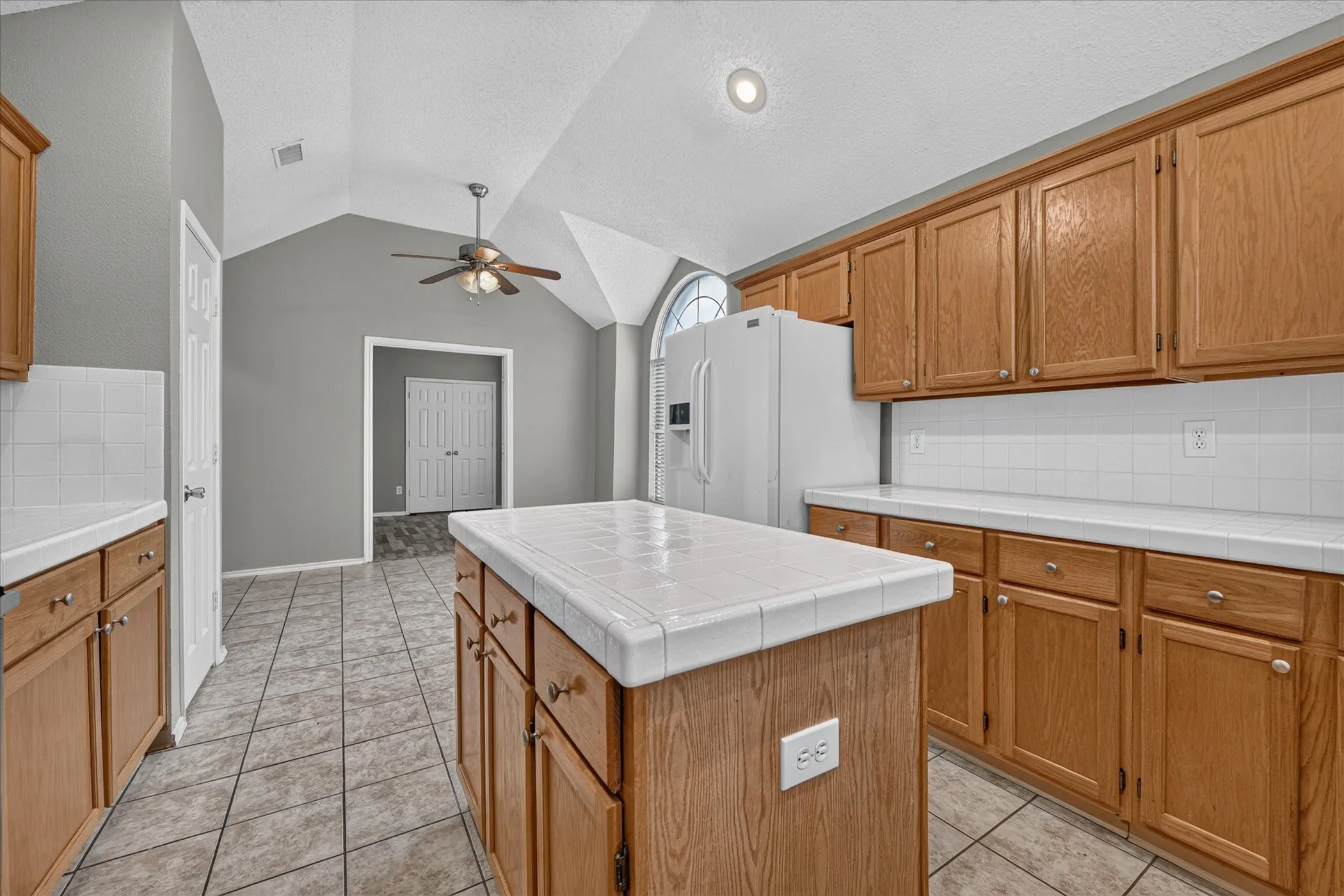 Kitchen featuring wood cabinetry, tile countertops, and a center island with a tiled surface