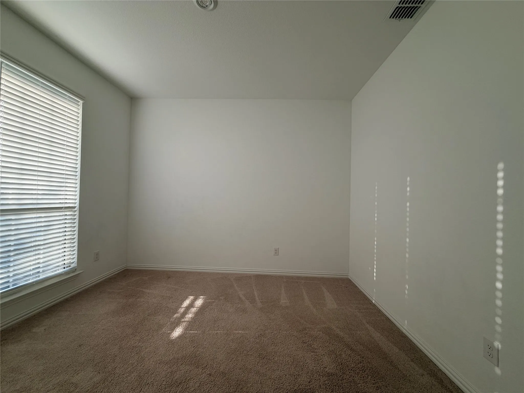 Wall-to-wall carpeting, recessed ceiling lighting, and a window with horizontal blinds