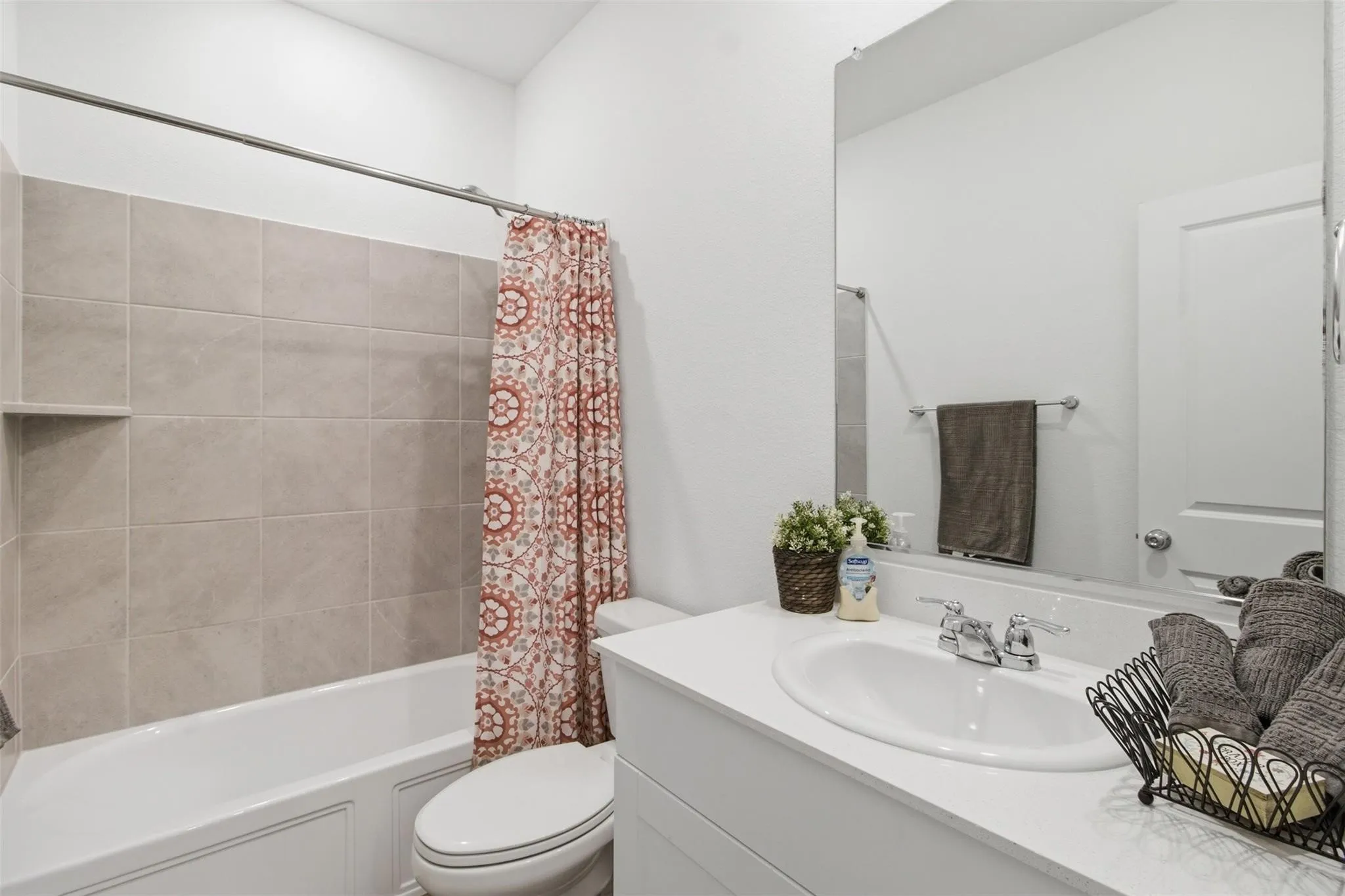 Integrated bathtub and shower with beige tiled surround and built-in niche
