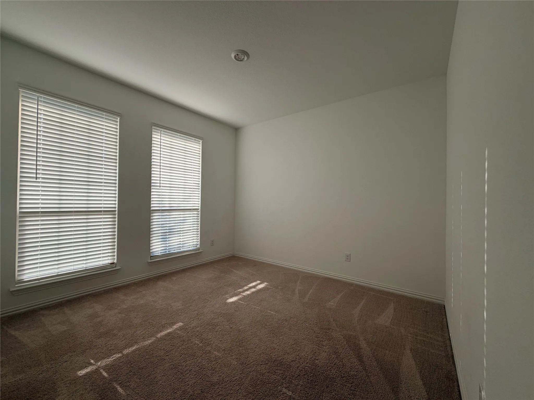 Room with two windows, carpet flooring, a recessed ceiling light, and white painted walls