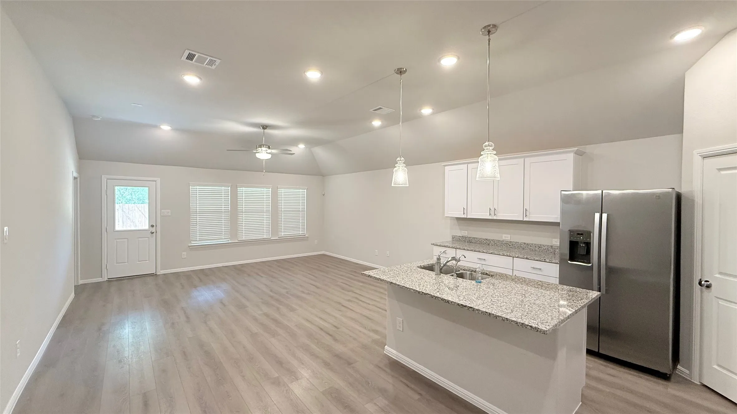 Open-concept living area featuring wood-finish flooring, recessed lighting, and a vaulted ceiling