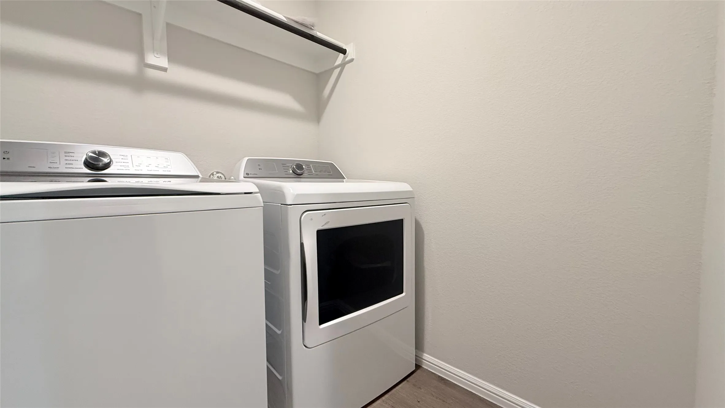 Dedicated laundry area featuring a wall-mounted shelving unit with a hanging rod