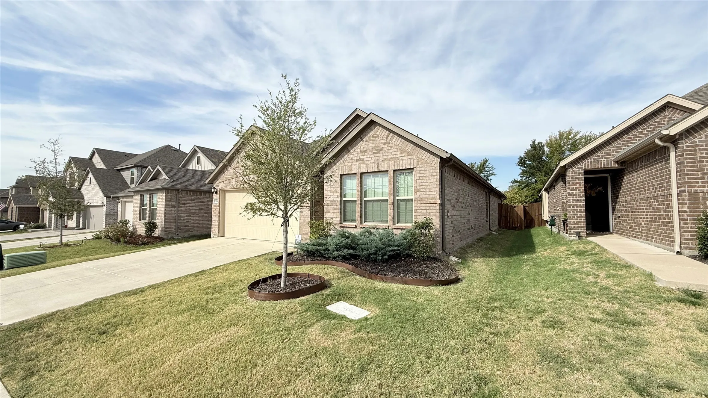Brick exterior with an attached garage, landscaped front yard, and concrete driveway