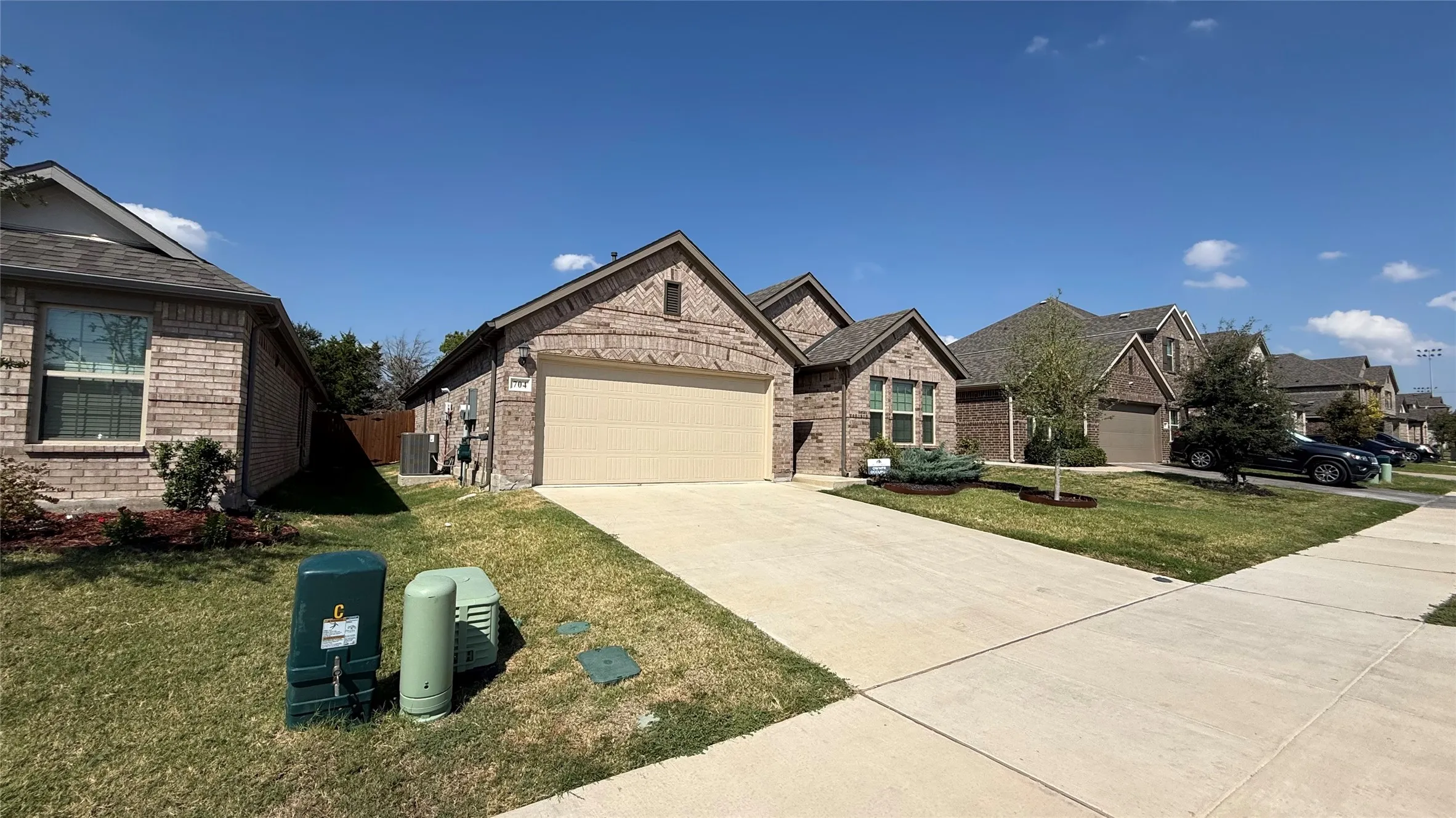 Brick exterior, attached garage, concrete driveway, and a well-maintained lawn