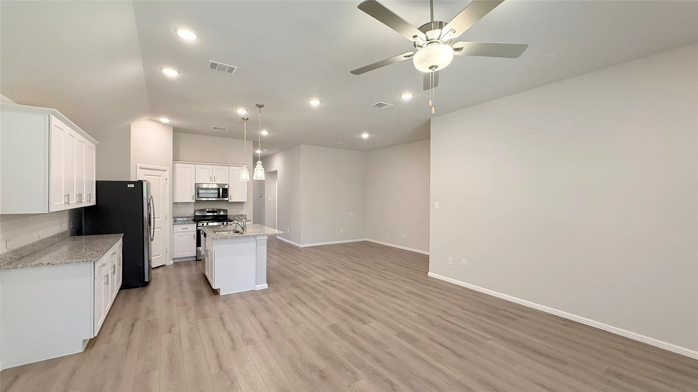 Open-concept living area with wood-finish flooring, recessed lighting, and a ceiling fan