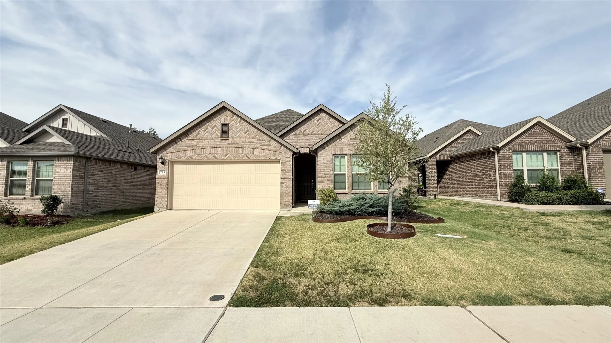 Brick exterior facade with a light-colored garage door and a concrete driveway