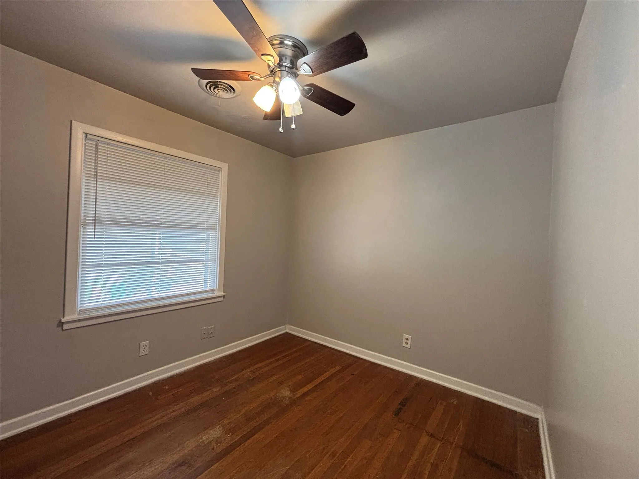 Wood-finish flooring, neutral wall tones, and a ceiling fan with integrated lighting