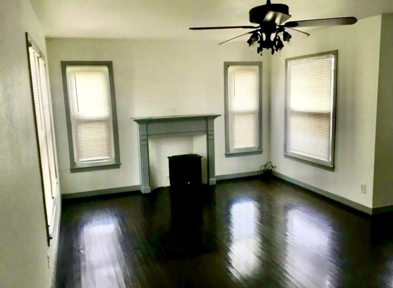 Dark wood-finish flooring, a decorative fireplace mantel, tons of natural light and ceiling fan.