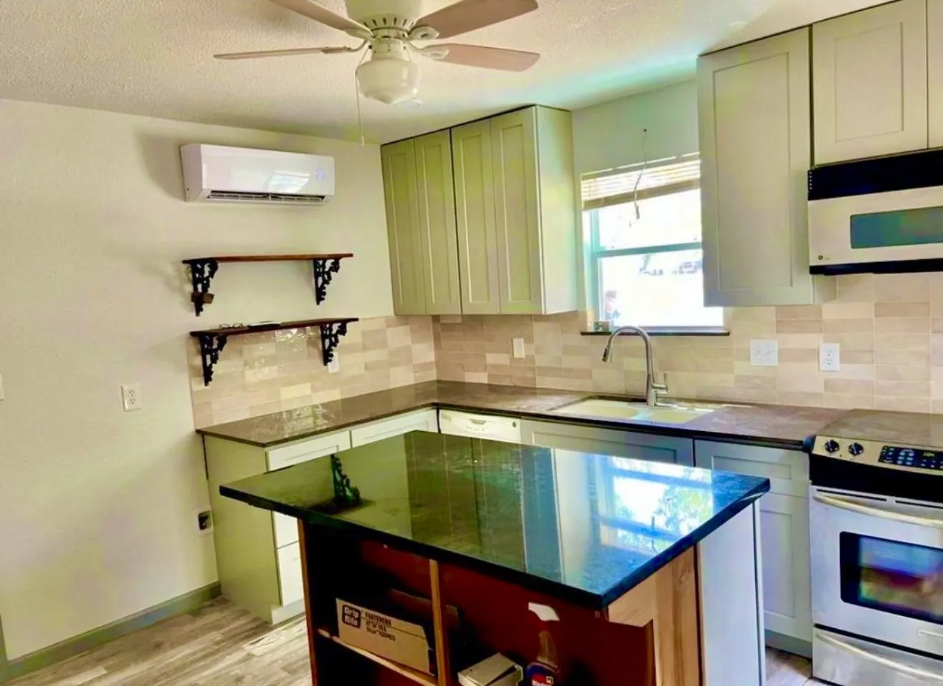 Kitchen featuring additional wall AC unit, decorative shelves, storage in kitchen island, backsplash and ceiling fan.