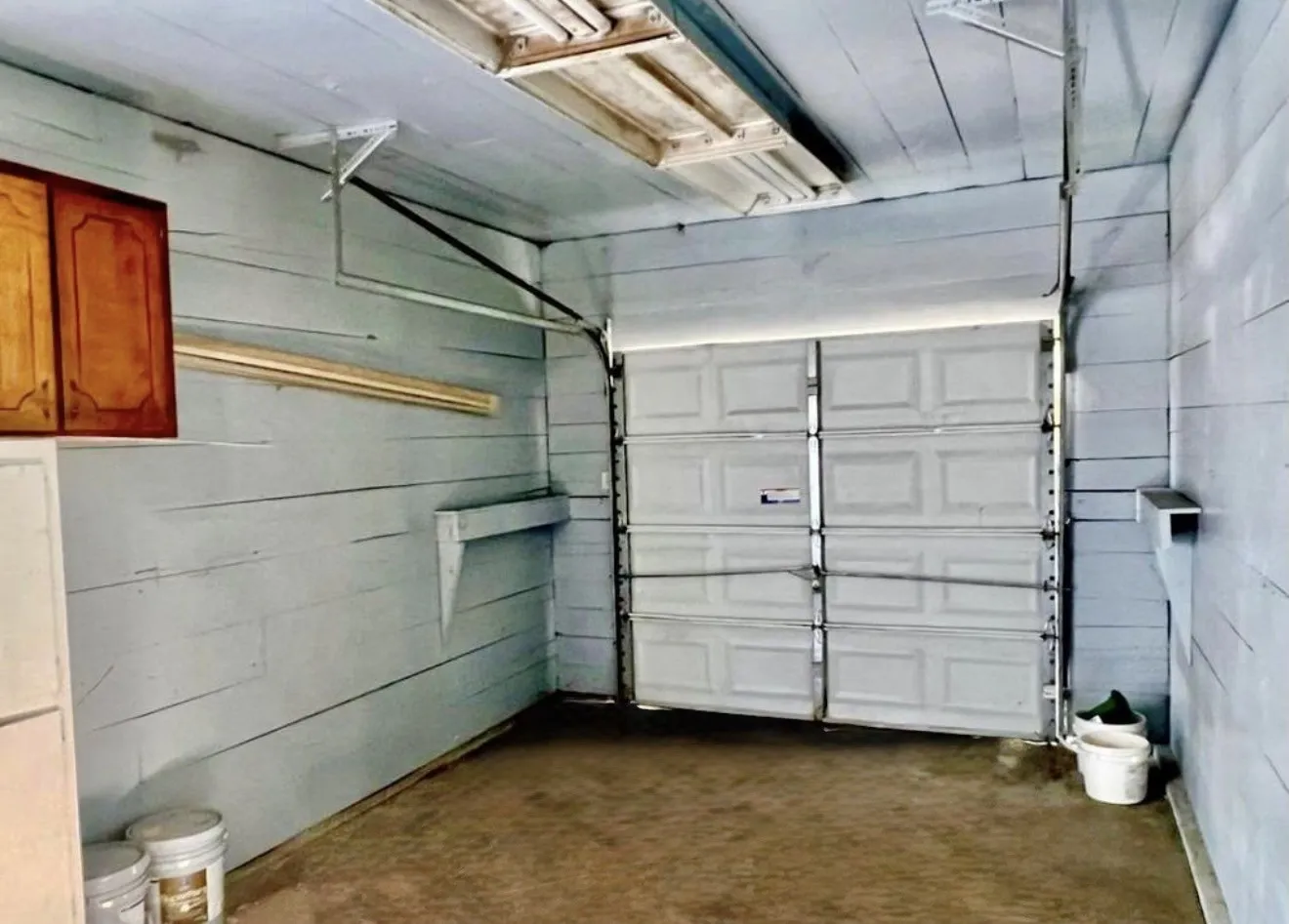 Interior garage space featuring a paneled overhead door, wood plank walls, and built-in shelving