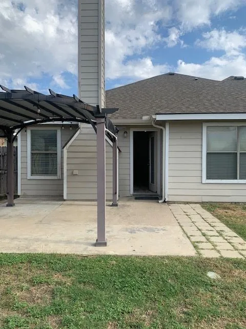 Backyard patio featuring a pergola, concrete slab, and paver walkway