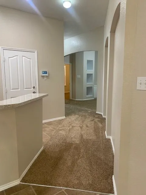 Hallway featuring arched wall openings and built-in shelving