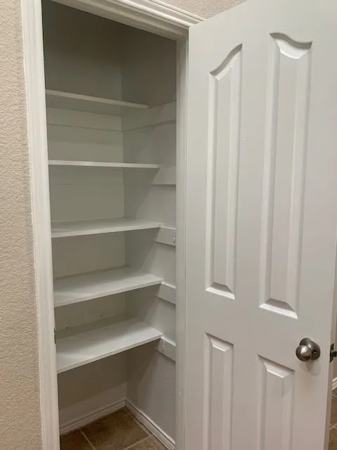 Built-in shelving with multiple levels, white paneled door, and textured wall finish