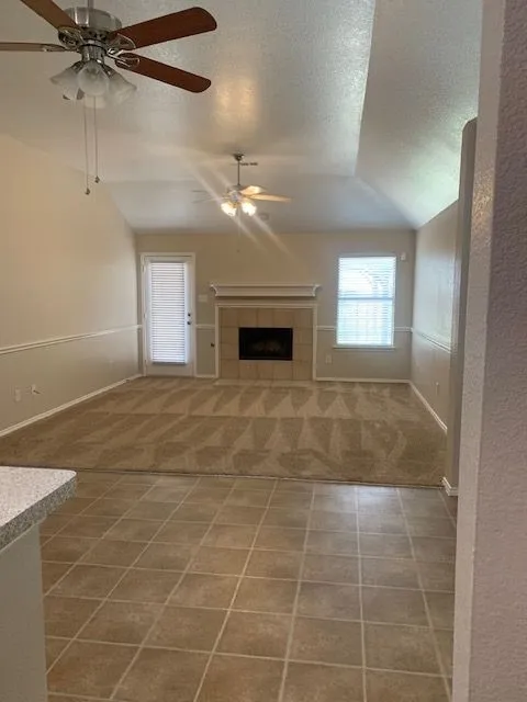 Vaulted ceilings with ceiling fans, fireplace with tile surround, and direct exterior access