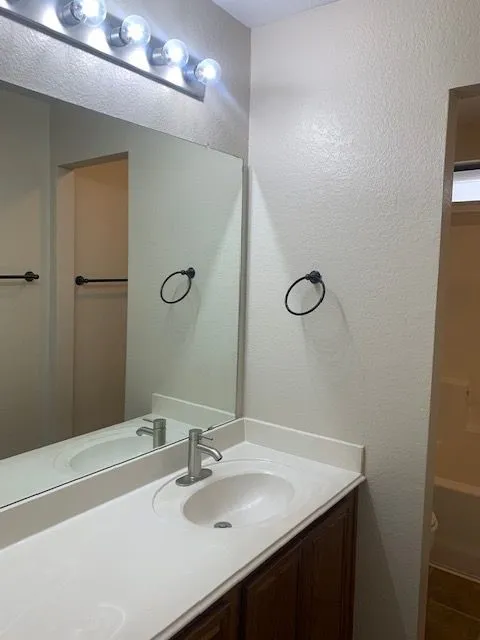 Modern bathroom vanity featuring a white quartz countertop, round undermount sink, and chrome faucet