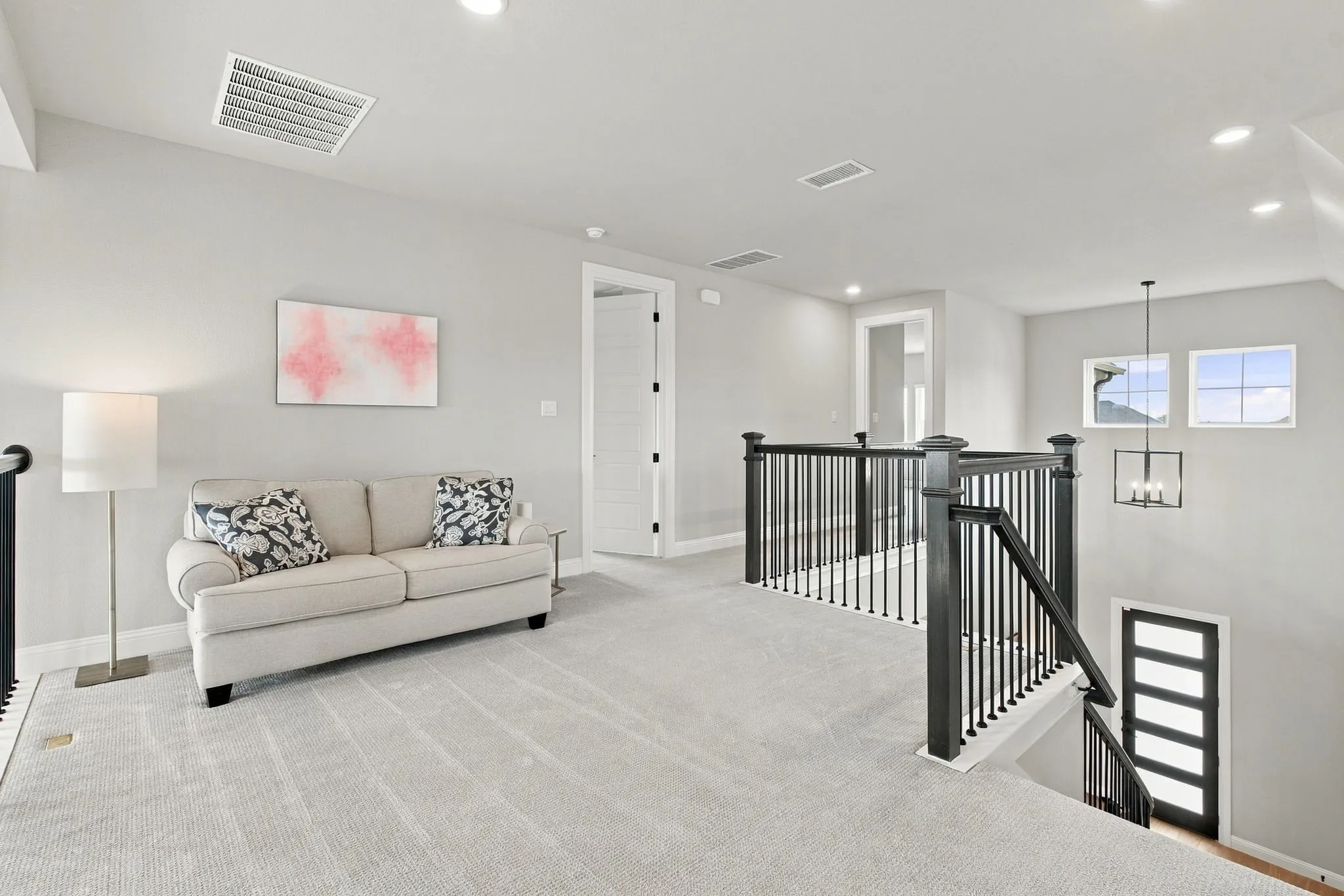 Carpeted loft area featuring recessed lighting, a modern staircase with dark wood newel posts and metal balusters, and a contemporary chandelier