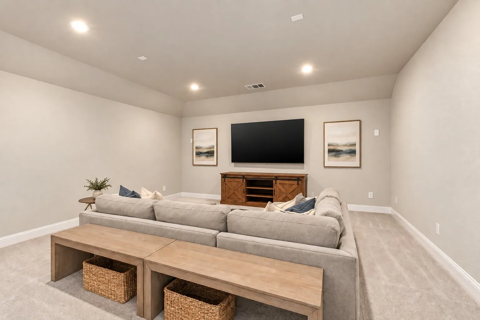 Recessed lighting illuminates this carpeted room, featuring neutral wall tones and a built-in entertainment console