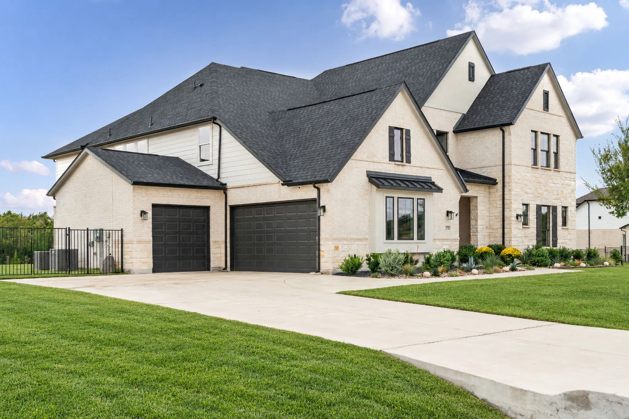 Stone and stucco exterior, dark shingle roof, landscaped front yard, and an attached two-car garage