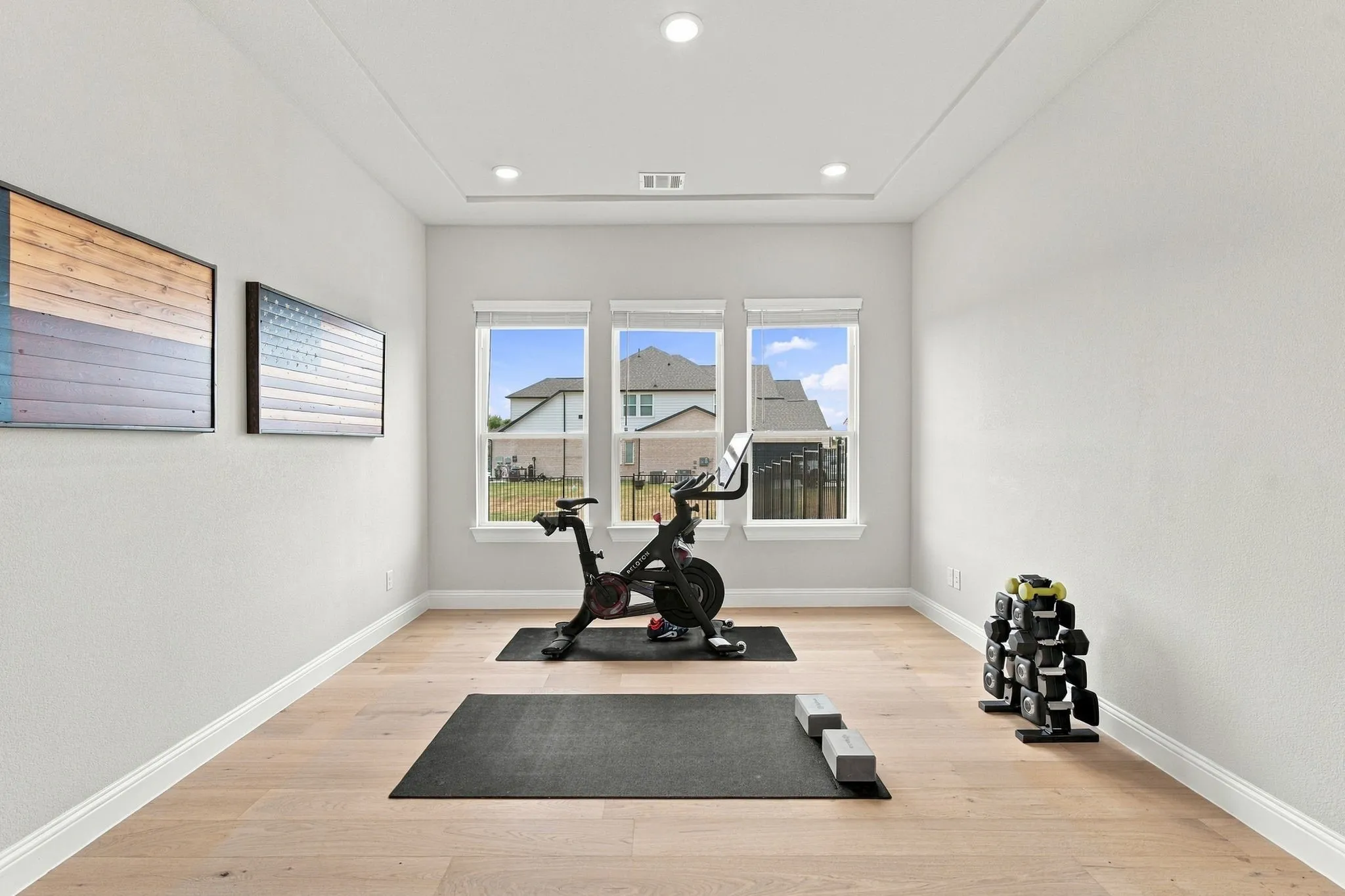Recessed lighting, tray ceiling, light wood-finish flooring, and multiple windows
