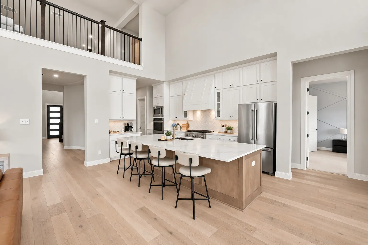 Kitchen featuring a large island with seating, stainless steel appliances, white cabinetry, and a tile backsplash