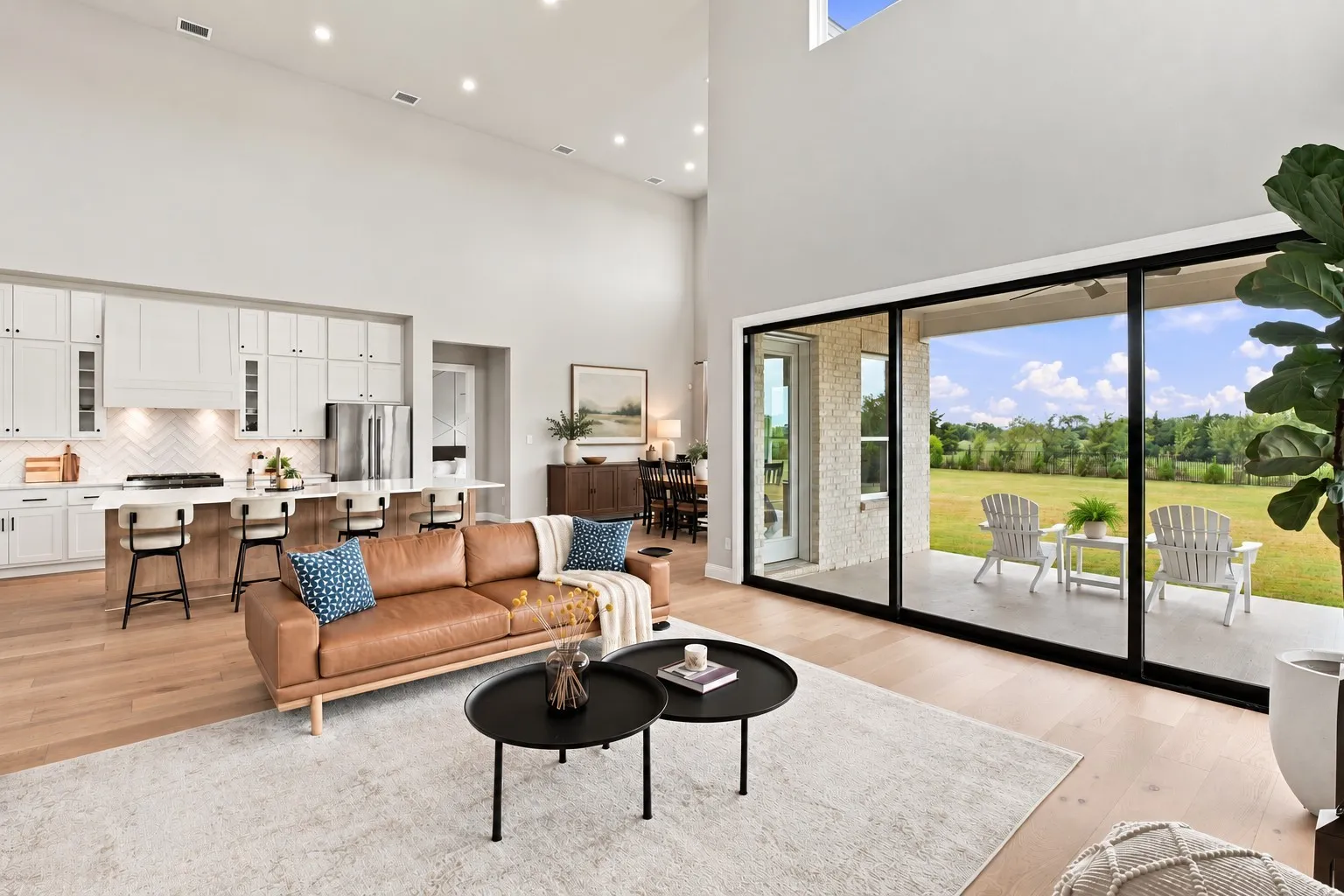 Vaulted ceilings, expansive glass sliding doors, wood-finish flooring, a kitchen island with seating, and white cabinetry