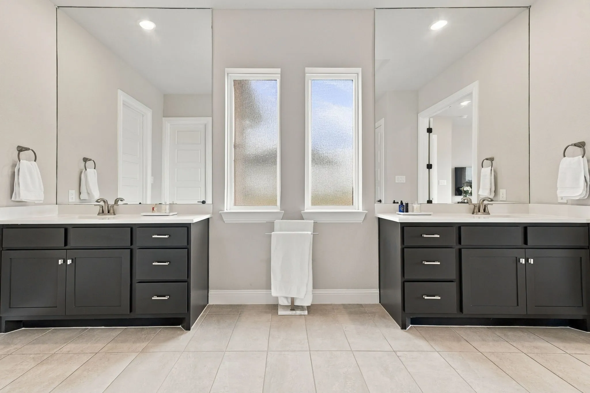 Dual vanities featuring dark cabinetry, undermount sinks, and light countertops