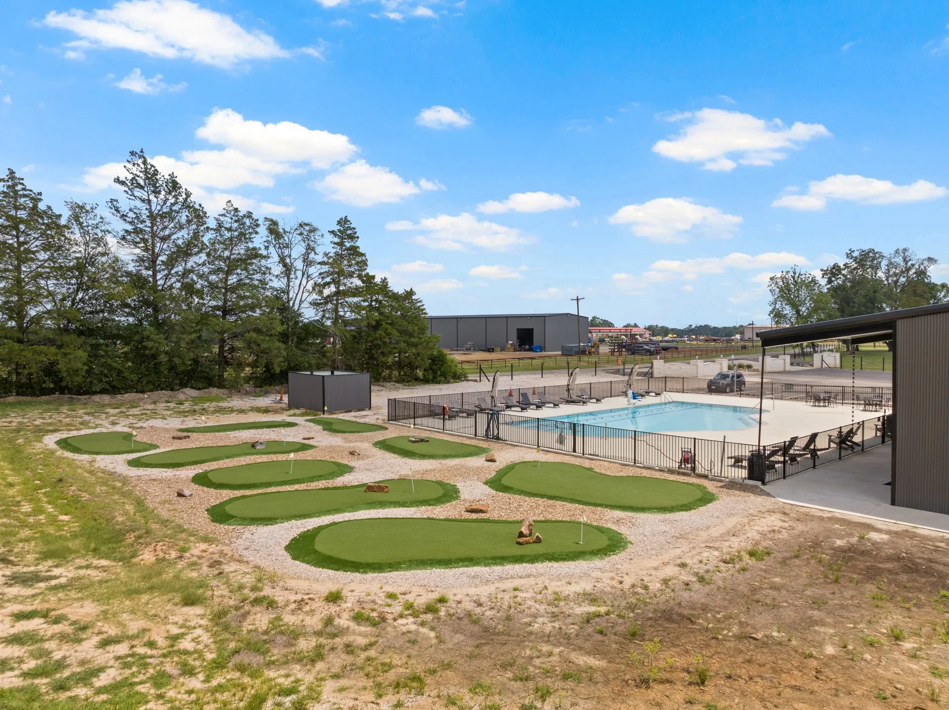 View of home's community with a swimming pool, a putting area, and a patio area