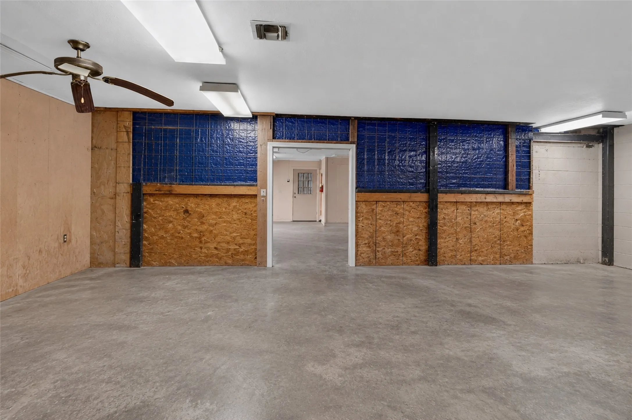 Concrete flooring, exposed plywood walls, ceiling fan, and recessed lighting - Virtually Cleared