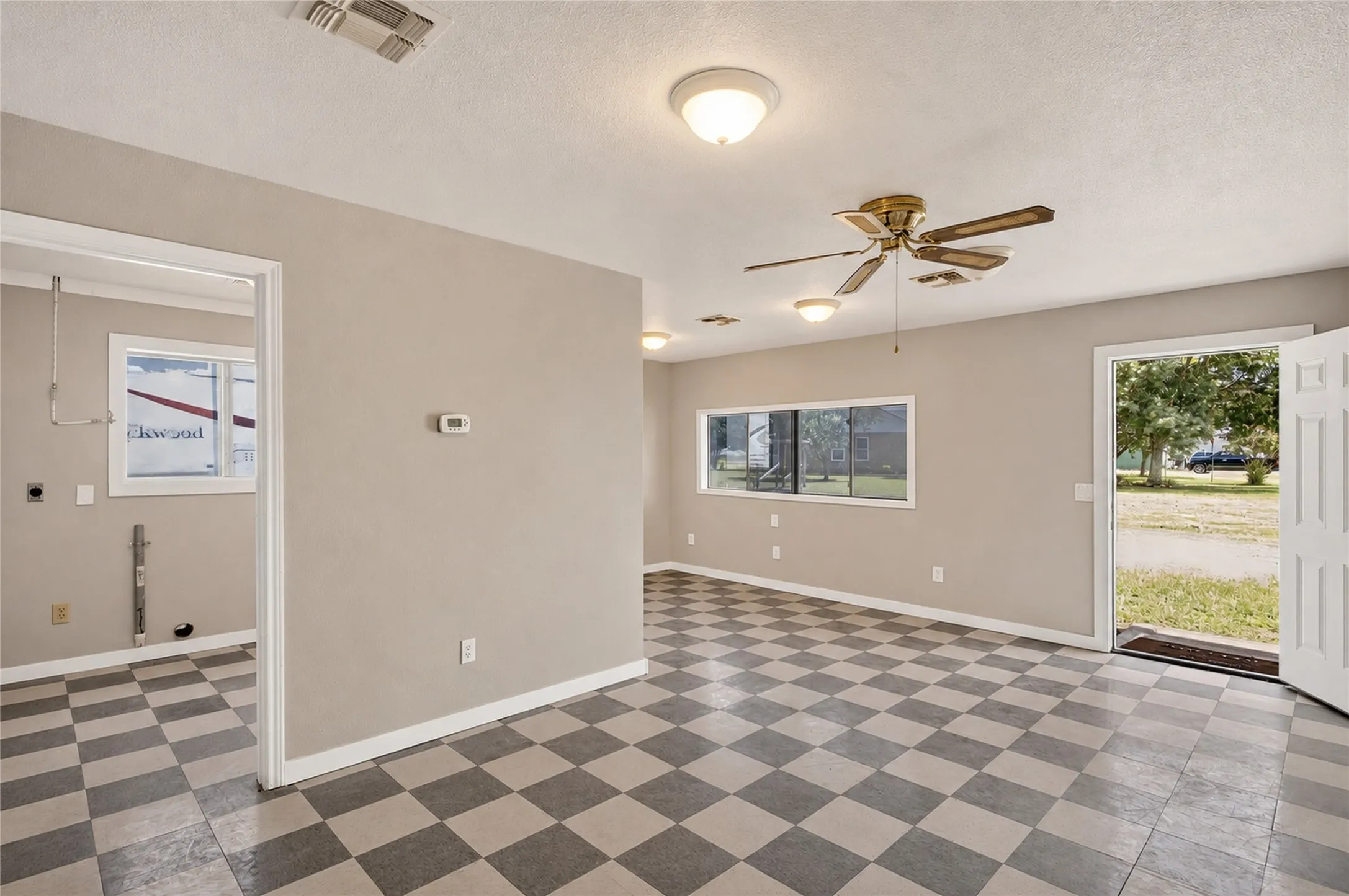Checkered tile flooring with a neutral wall color, overhead lighting, a ceiling fan, and multiple windows providing natural light
