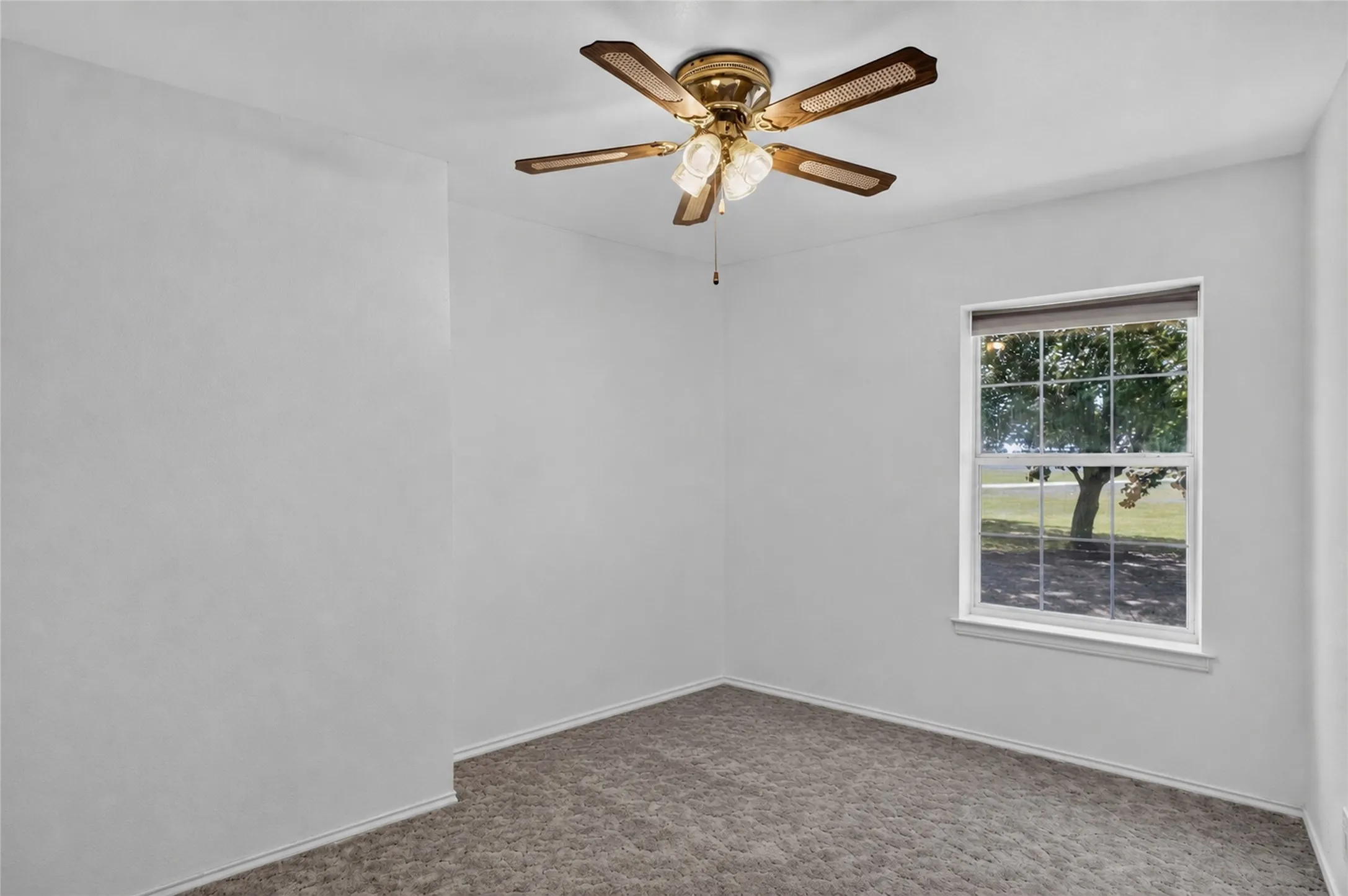 Window with outdoor scenery, ceiling fan with integrated lighting, wall-to-wall carpeting, and white walls - Virtually Cleared