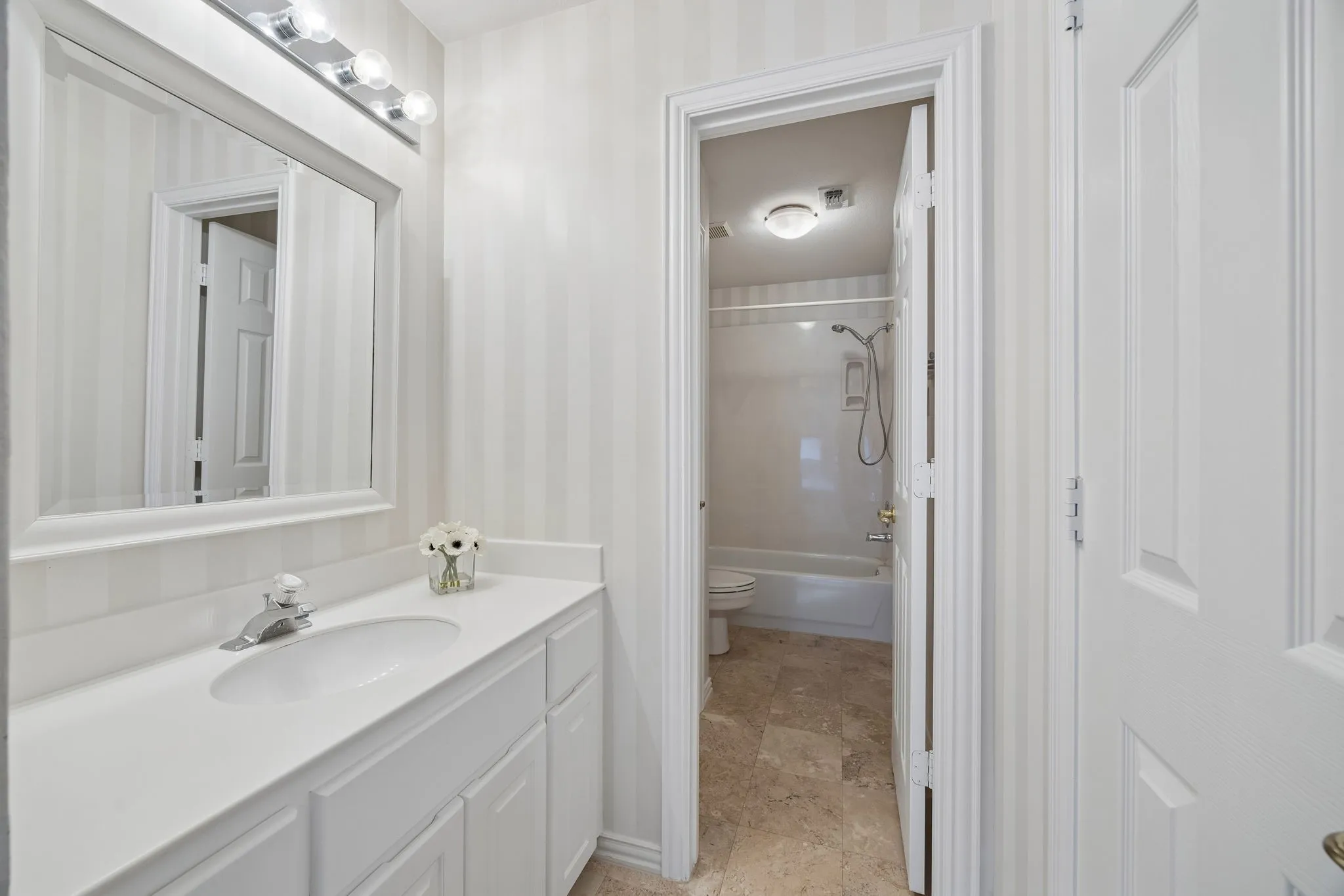 Vanity area of the jack and jill bathroom looking through to the shared watercloset with tub with shower.