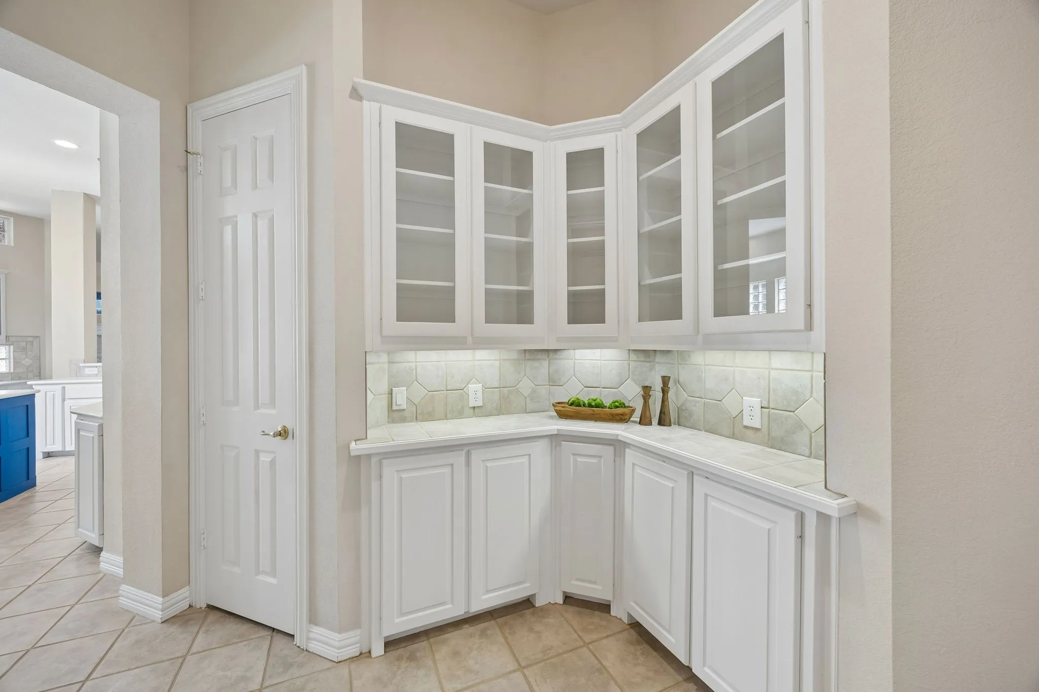 The Butler's pantry offers wonderful space for storing fine china and other treasures in the glass front cabinets as well as storage for service pieces. The counter gives space for staging courses for a dinner or to set out a buffet. The door shown to the left opens to under the stair storage including additional pantry shelving.
