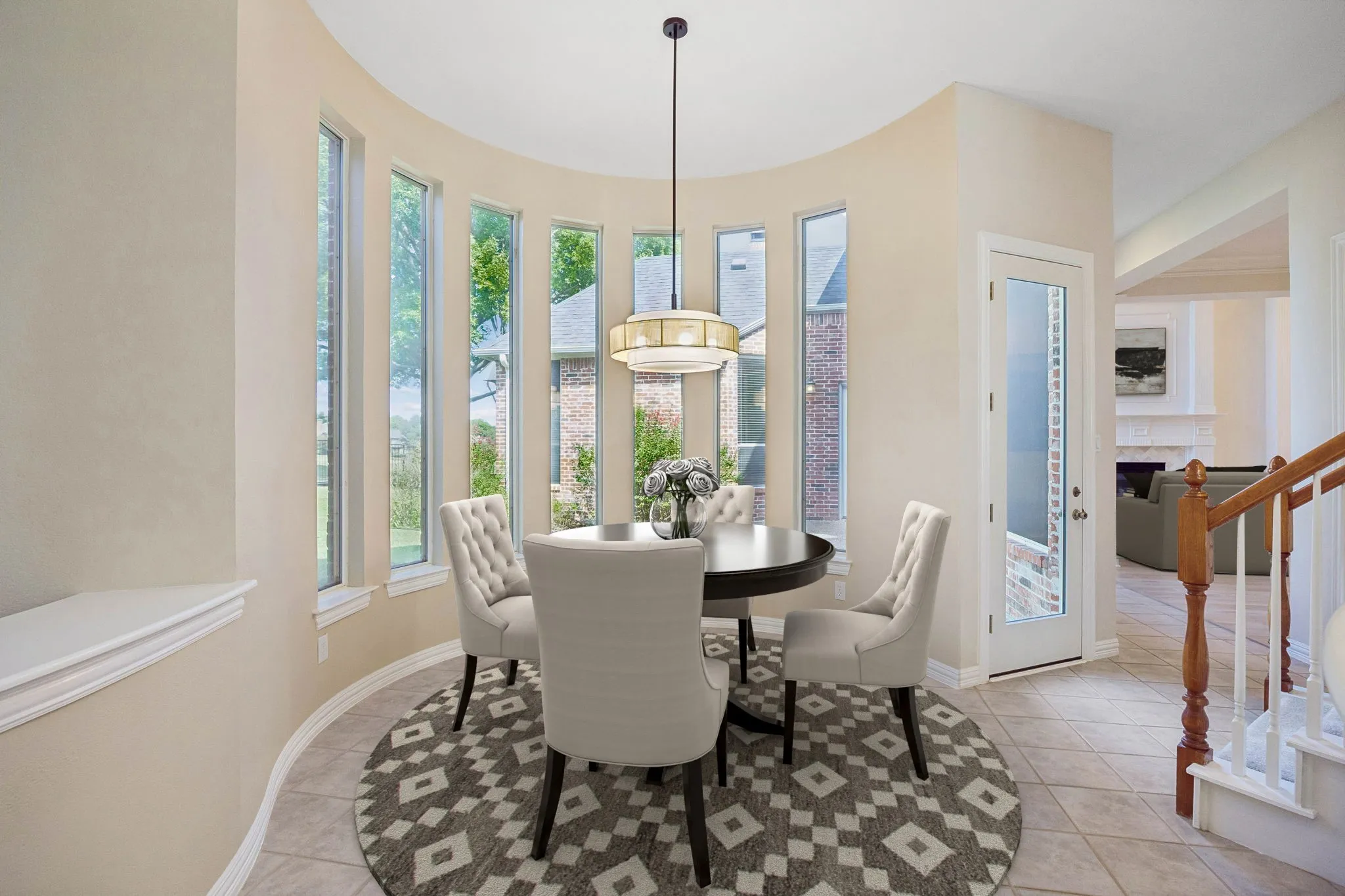 The graceful curved lines found through out the home are repeated in the casual dining area. Enjoy gorgeous views of the backyard. The room also enjoys a whimsical light fixture and the pony wall on the left of the picture can provide additional serving area between the kitchen, nook and sitting room. (Virtually staged to show potential.)