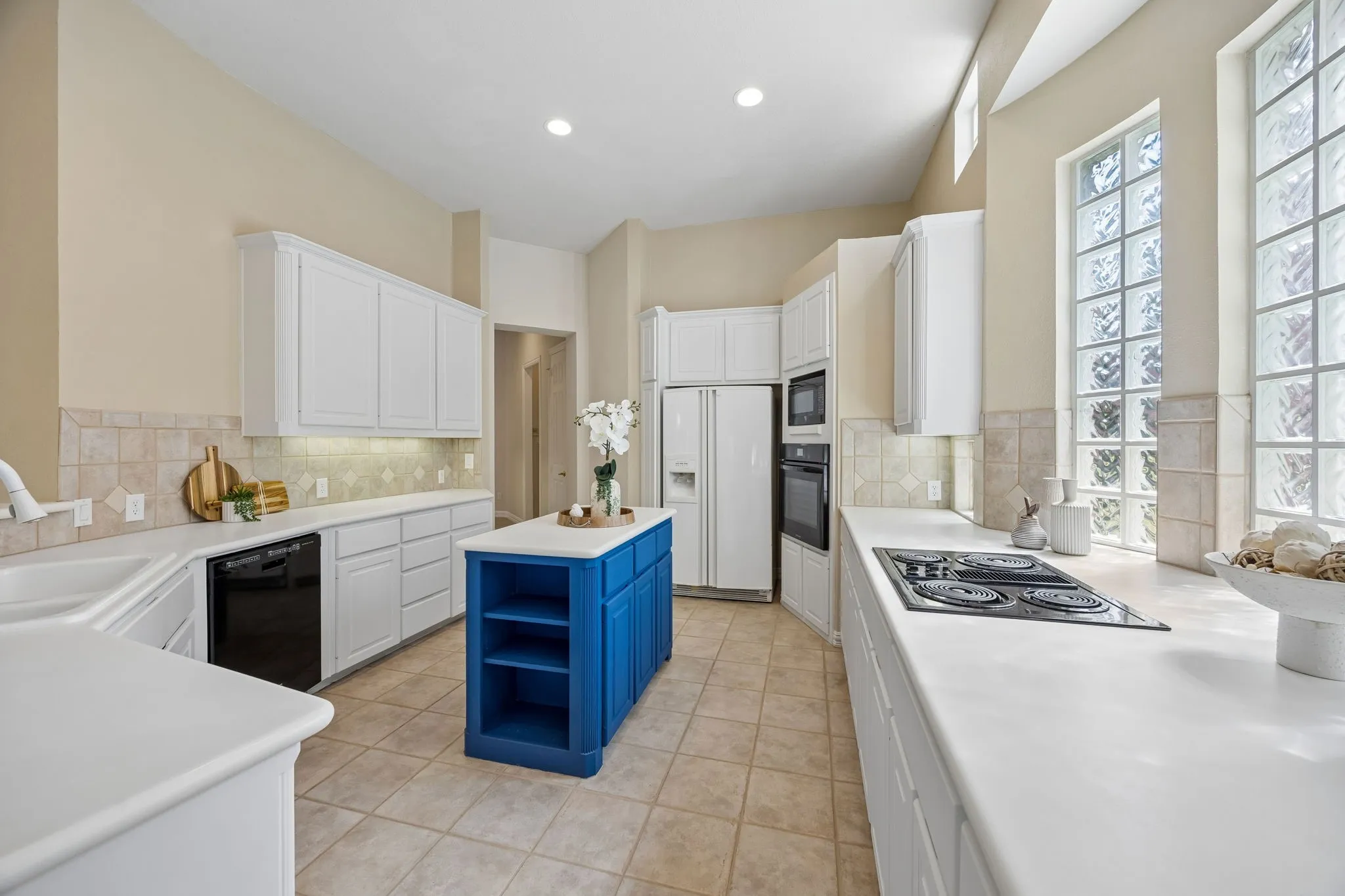 This kitchen enjoys wonderful natural light from the glass block windows. The room also benefits from recessed lighting. Appliances include convection oven, microwave, electric cooktop and dishwasher. The primary pantry is found through the door shown in the background.
