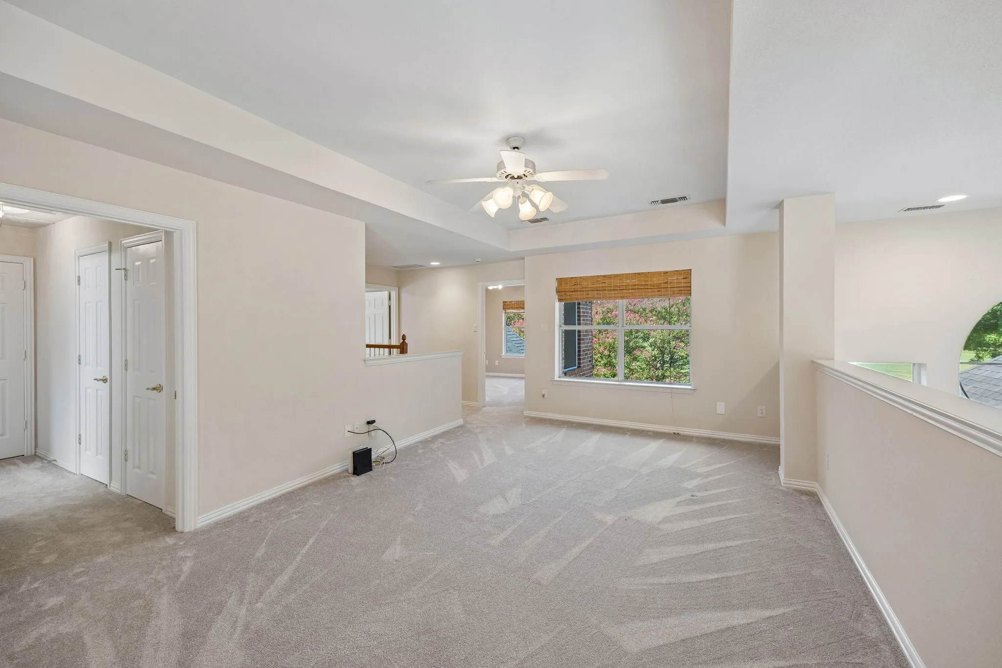 The second floor game room has carpet, ceiling fan and is open to the first floor.