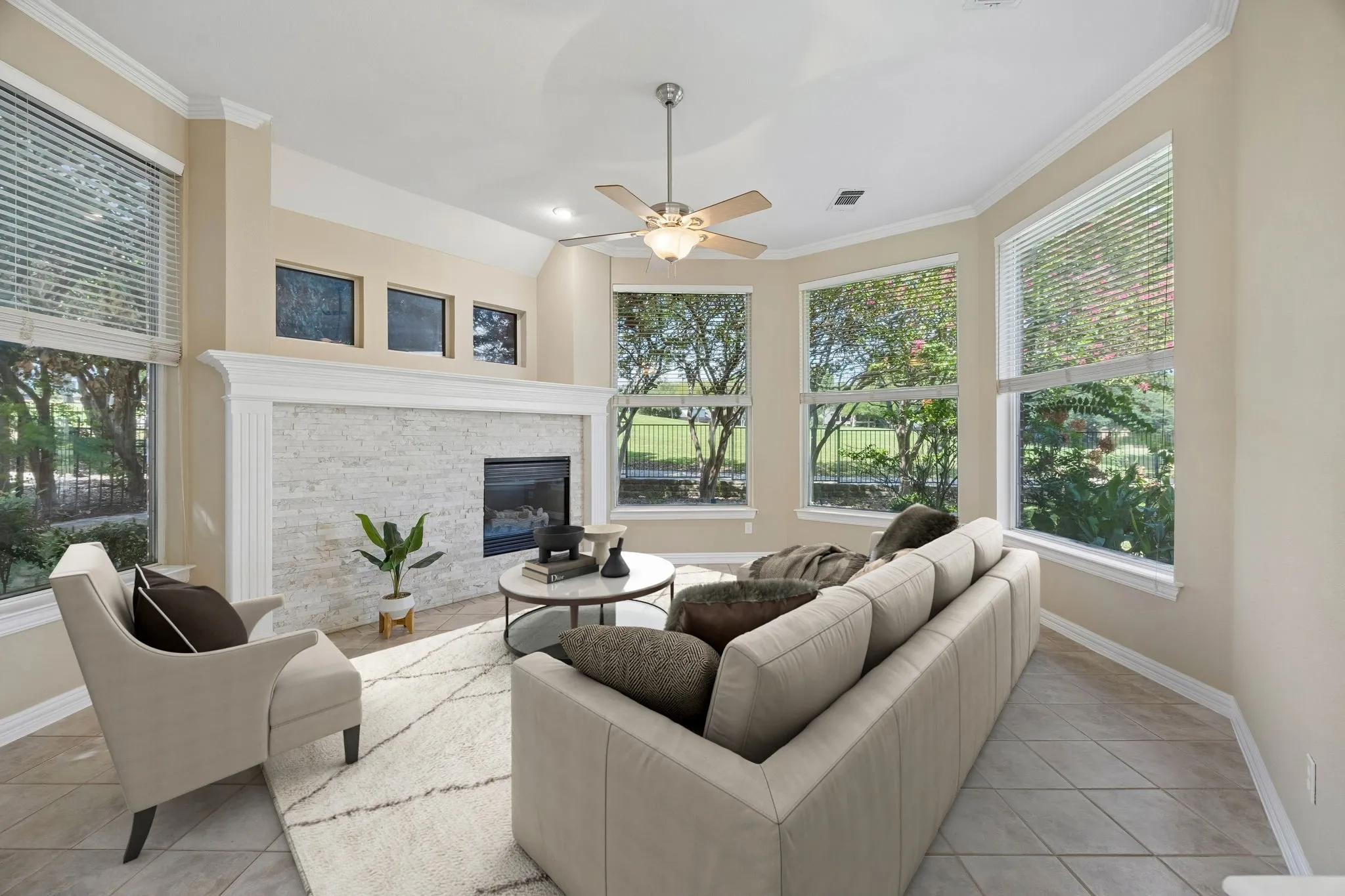The family room at the back of the home also enjoys the curved lines found in the home. The large windows overlook mature trees and the golf course beyond. The fireplace with gas logs and stacked stone surround provide a cozy feel for the room. Other features include ceiling fan, crown molding and easy care tile flooring. (Virtually staged to show potential.)