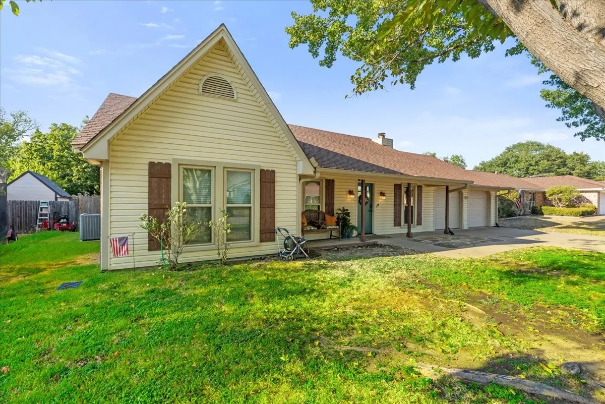 Siding exterior with decorative shutters, covered front porch, attached two-car garage, and established landscaping