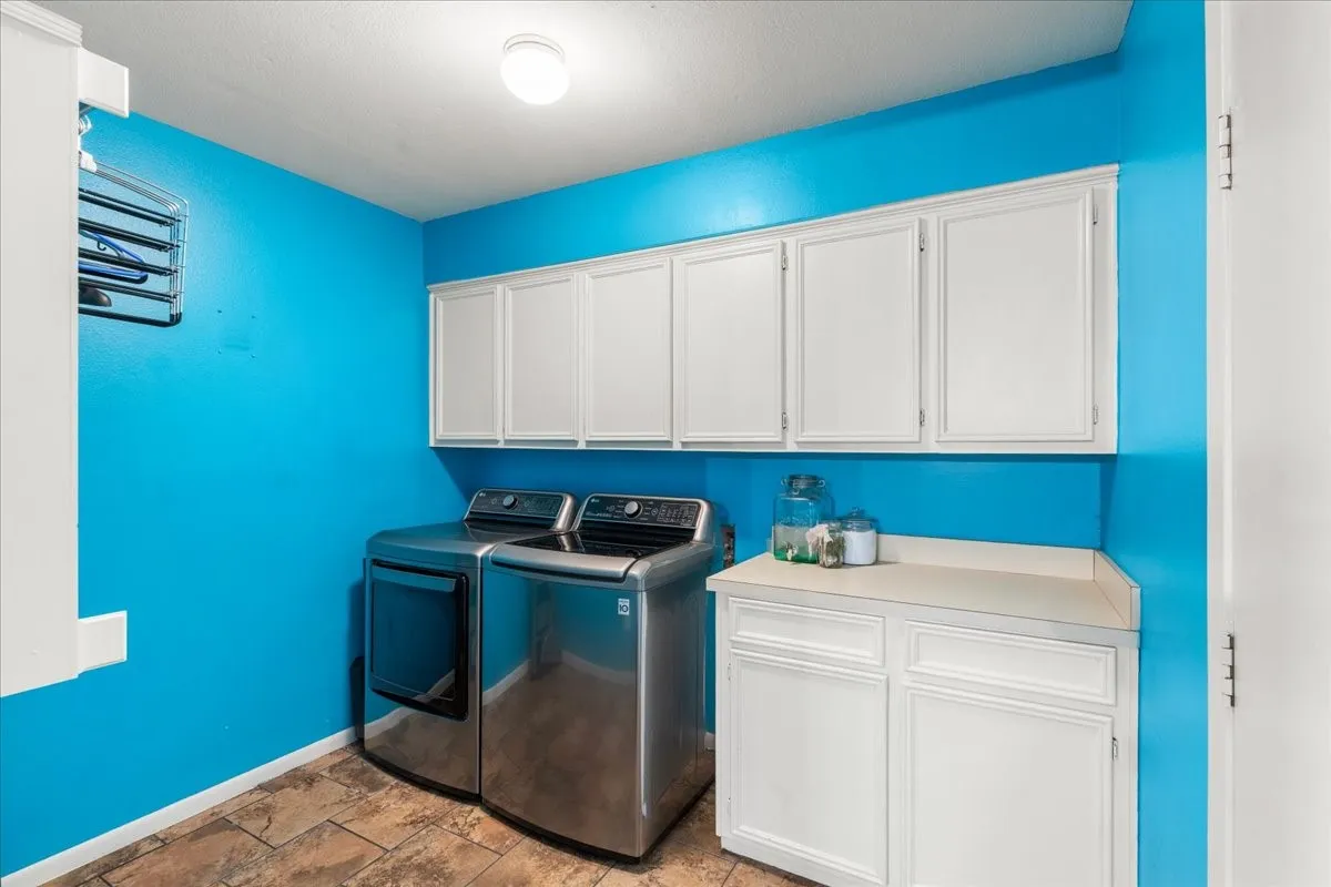 Laundry area featuring white cabinetry, a light-colored countertop, and patterned floor tiles