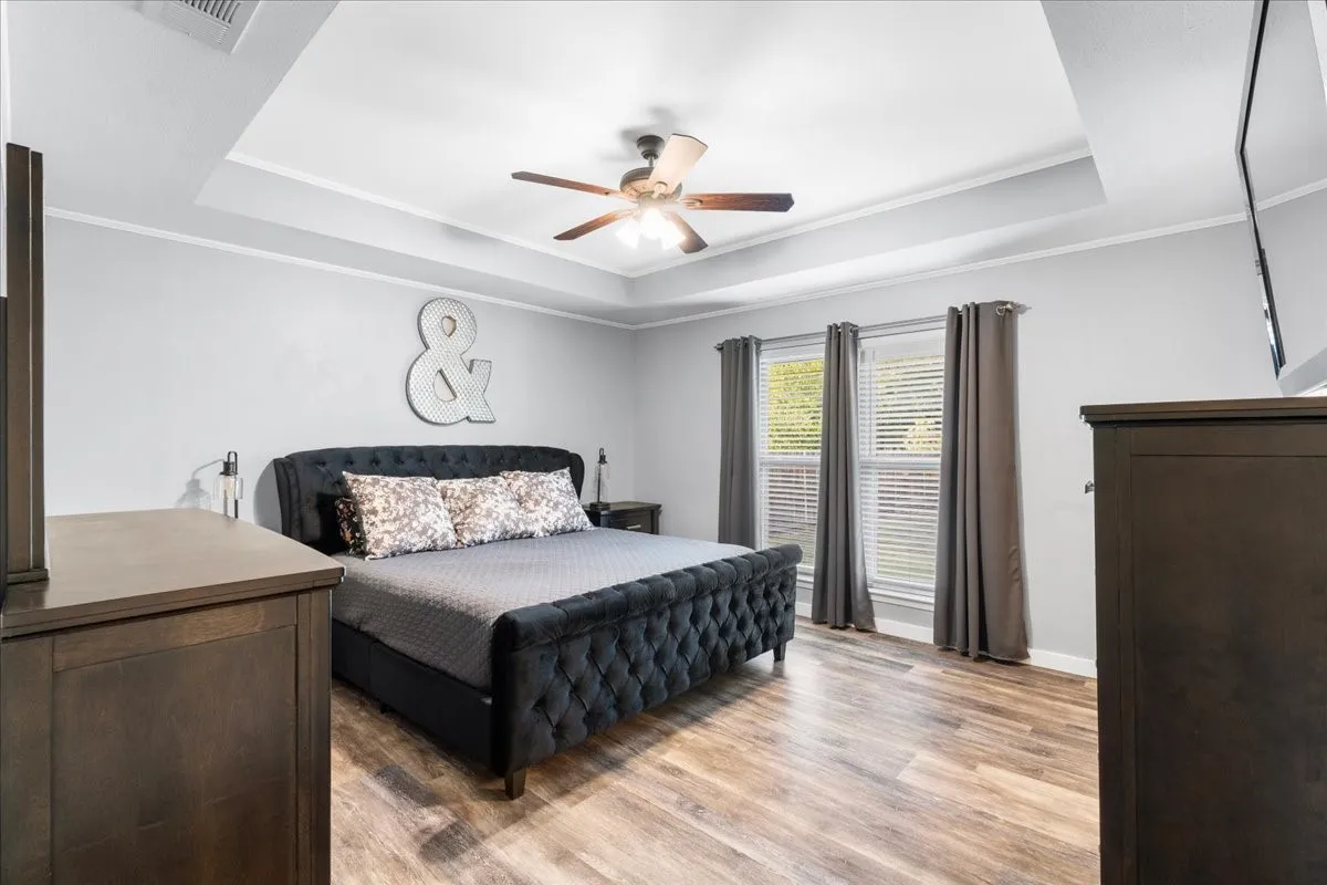 Tray ceiling with crown molding, wood-finish flooring, and recessed lighting
