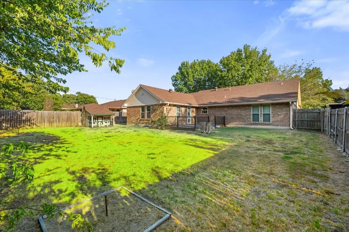 Expansive backyard featuring a grass lawn, wood fencing, and a detached storage shed