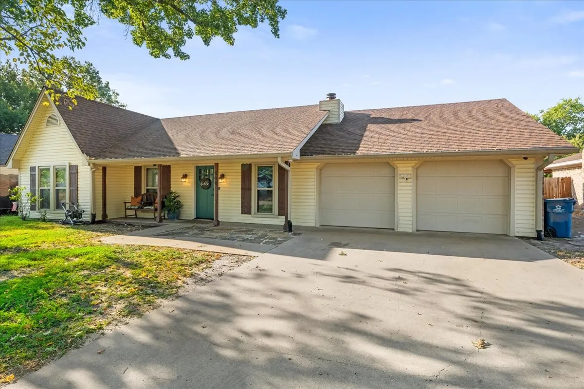 Light-colored siding exterior with a contrasting teal front door, dark brown shutters, and an attached two-car garage