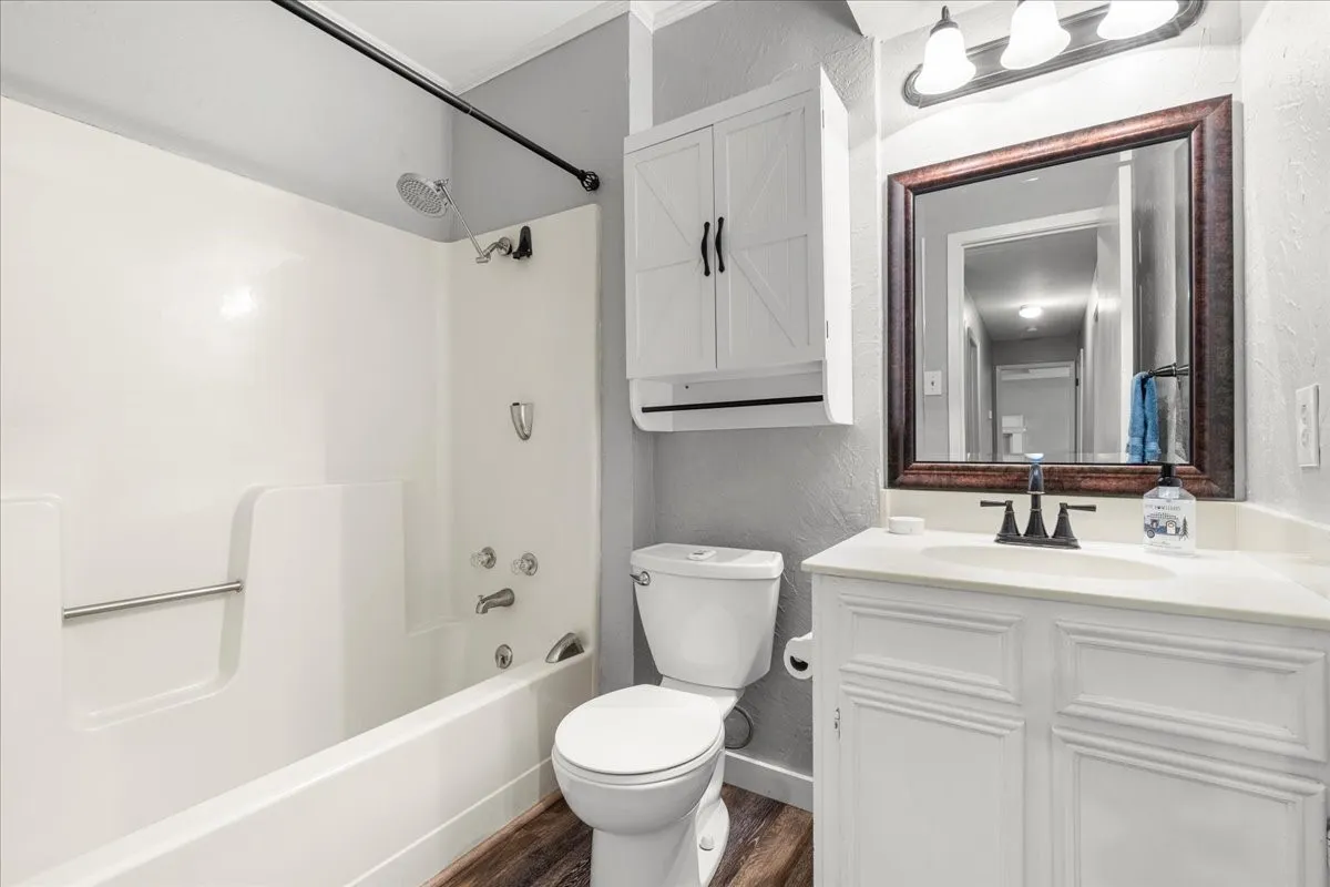 White vanity with an integrated sink and dark bronze faucet, framed mirror, and a wall-mounted light fixture
