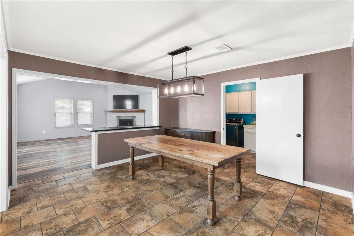 Tiled flooring with a rectangular light fixture, leading to a living area with wood-finish flooring and a fireplace
