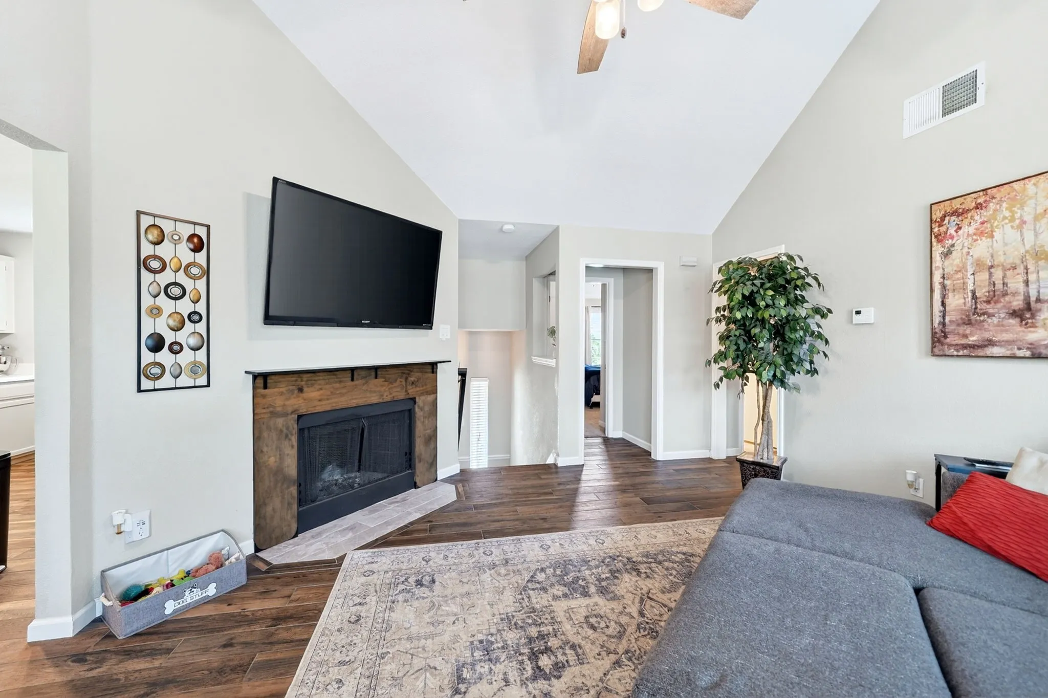 Vaulted ceiling with a ceiling fan, fireplace with a wood mantel, wood-finish flooring, and recessed lighting